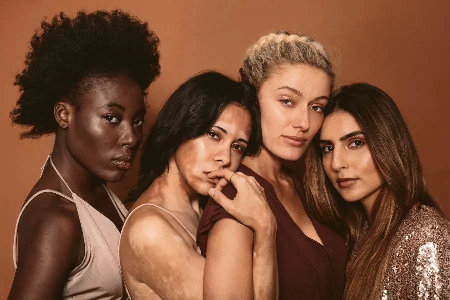 Different women all together close to each other and looking into the camera.